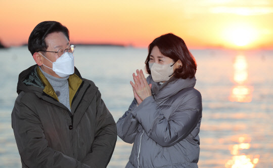 더불어민주당 이재명 대선후보가 부산경남 방문 이틀째인 2일 부산시 사하구 다대포해수욕장에서 부인 김혜경 씨와 함께 '2022 글로벌 해돋이 : 지구 한 바퀴' 온라인 해맞이 행사에서 떠오르는 태양을 배경으로 박수치고 있다. 연합뉴스
